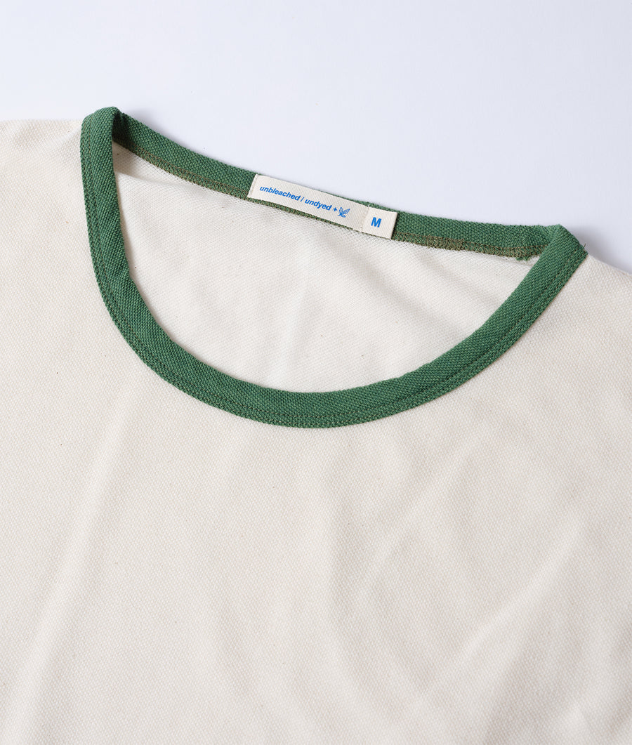 A close-up detail shot of a white crew neck t-shirt with a green trim collar and size tag - Industry of All Nations