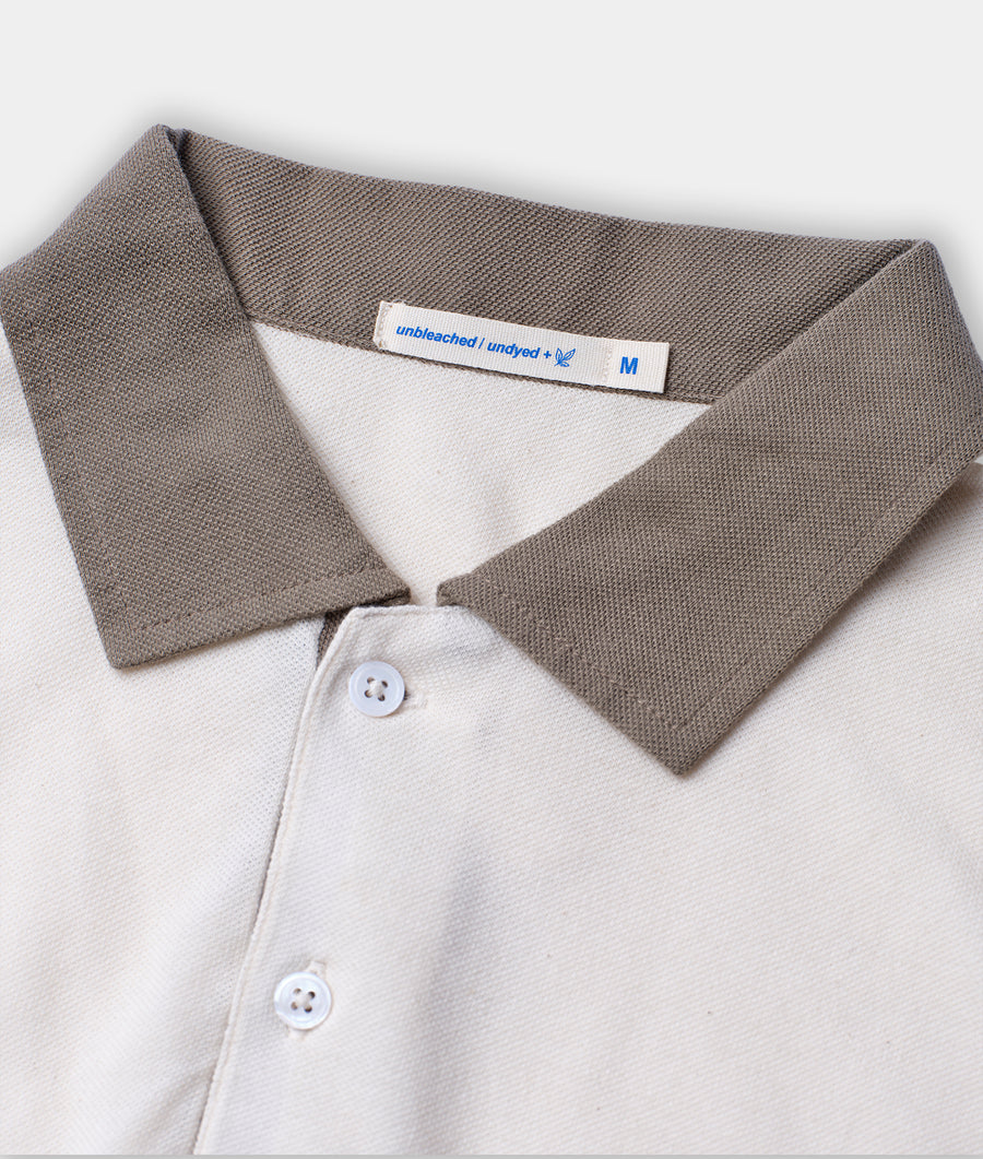 Closeup detail shot of a gray and white cotton polo shirt with a collar and buttons, displayed flat - Industry of All Nations