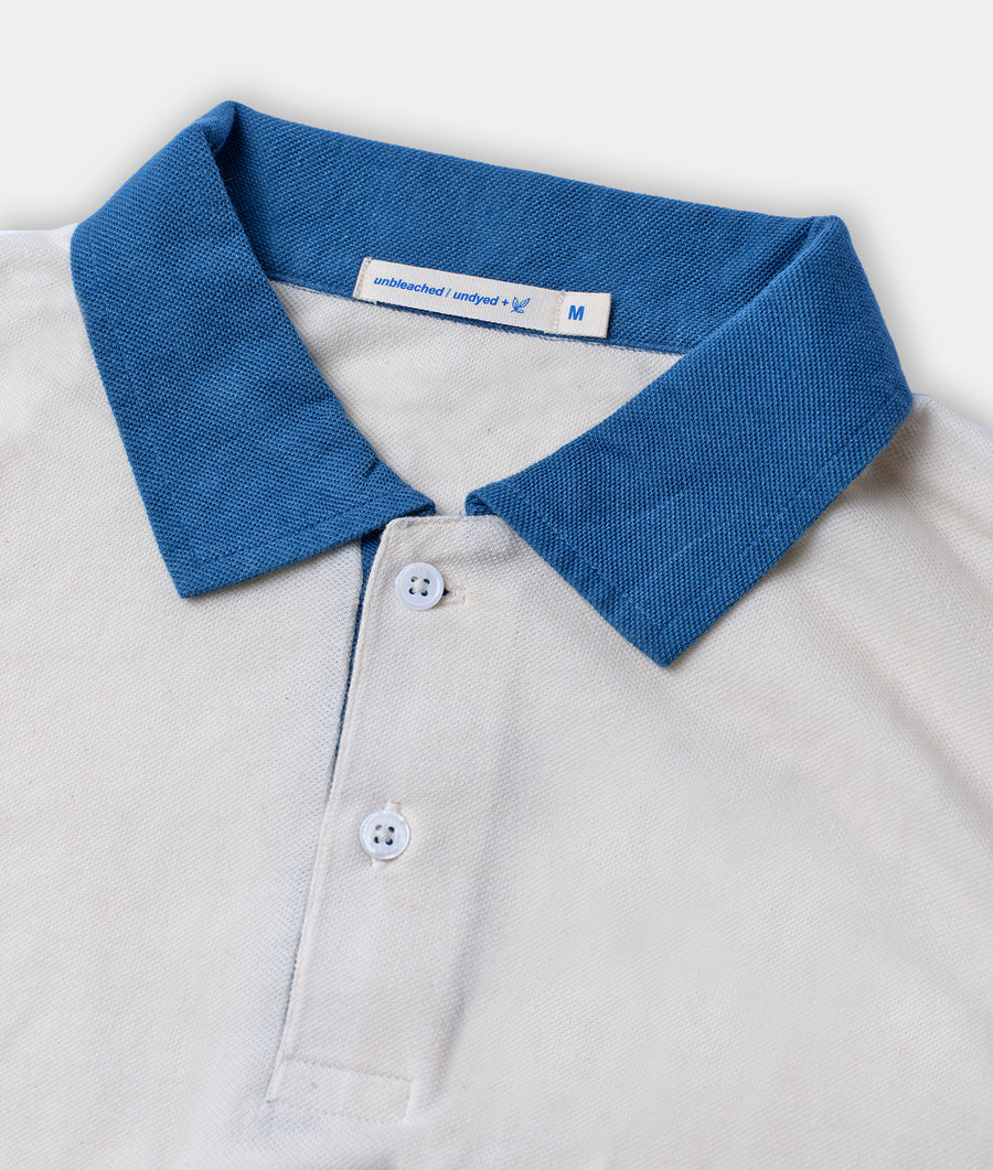 A close-up detail shot of a white and blue polo shirt with a button collar - Industry of All Nations