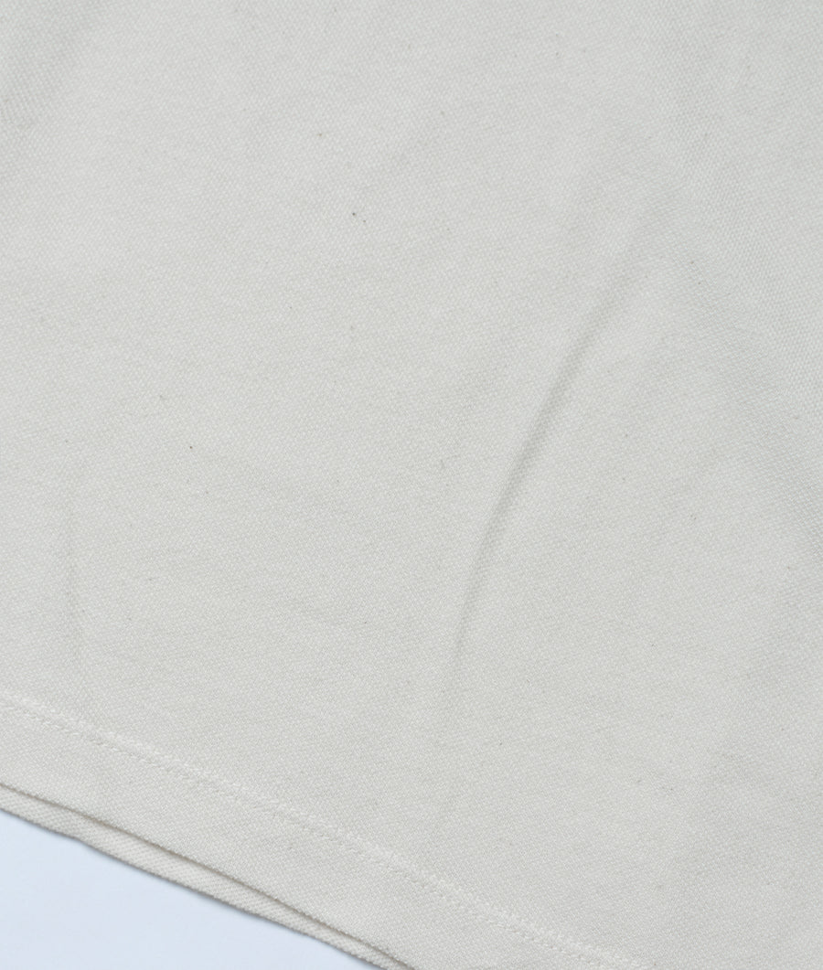 Flat lay image showing a plain, off-white organic cotton fabric with a slightly textured surface and subtle wrinkling - Industry of All Nations