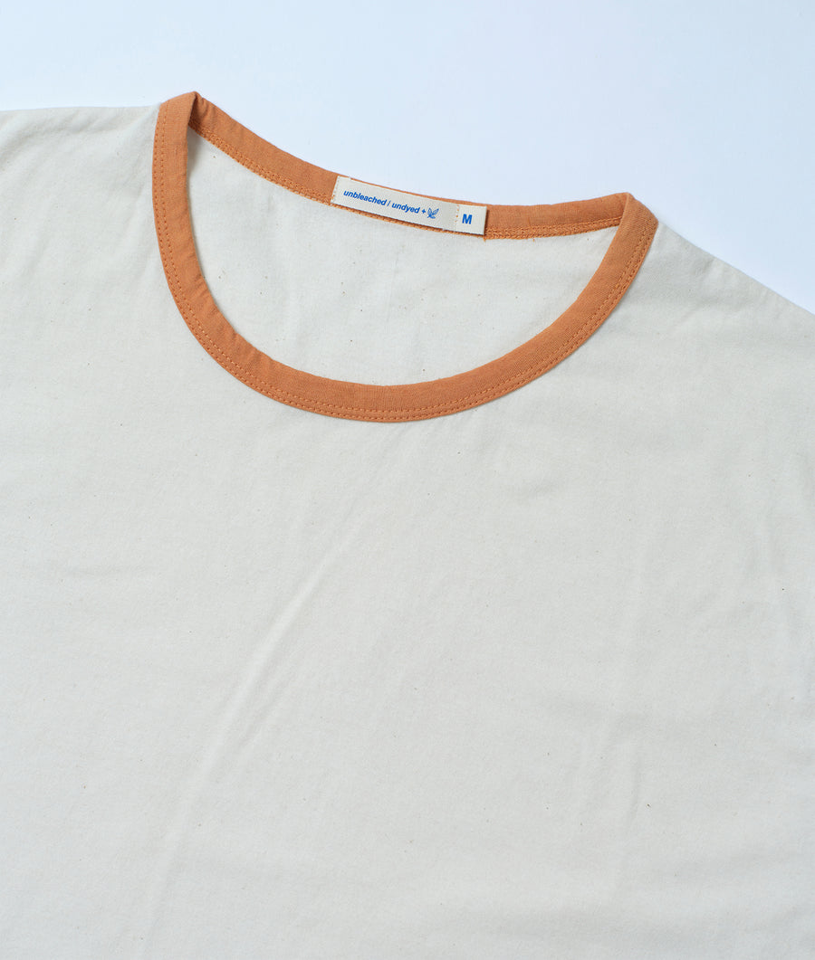 A close-up detail shot of the neckline of a plain white organic cotton t-shirt with a burnt orange trim - Industry of All Nations