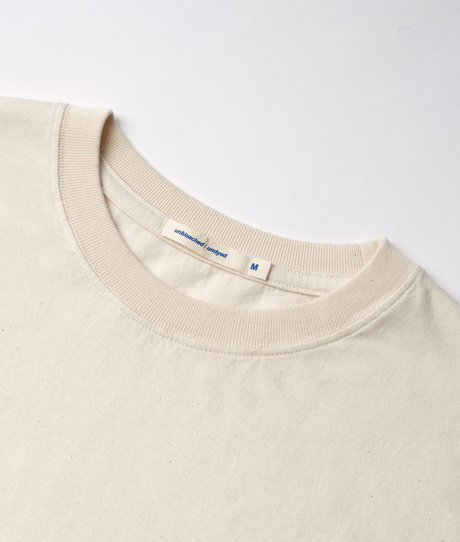 Detail shot of a cream-colored, unbleached and undyed t-shirt from Industry of All Nations.