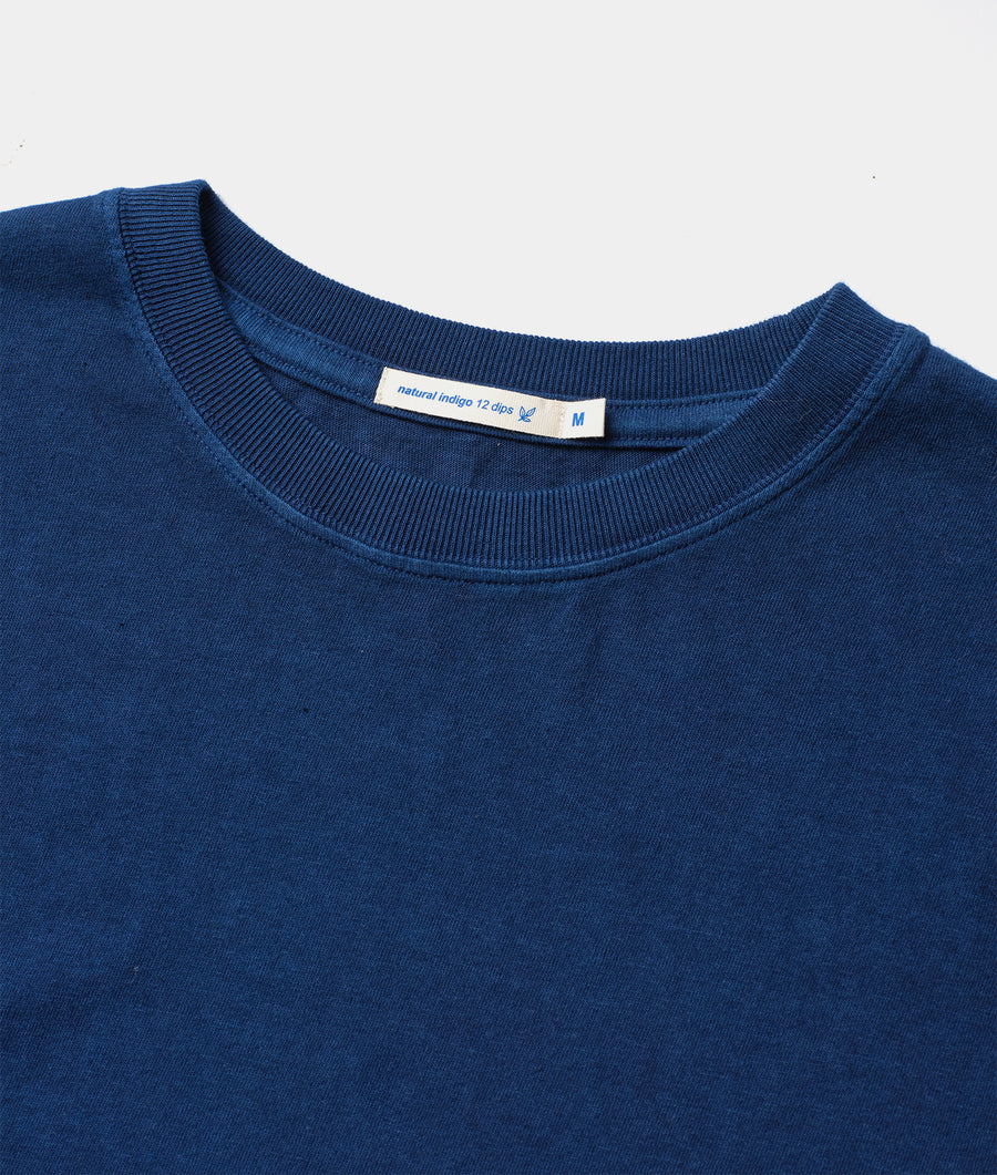 A blue crewneck sweater with a natural indigo dye label, displayed as a flat lay - Industry of All Nations