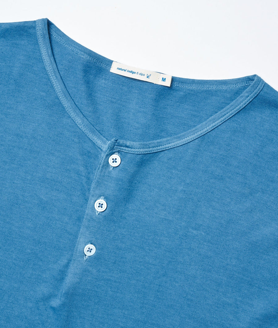 A close-up detail shot of a blue cotton t-shirt with three white buttons at the neckline - Industry of All Nations