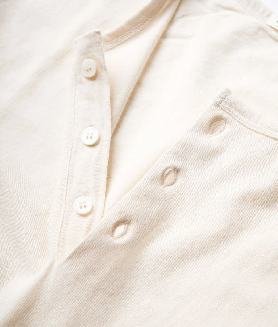 A close-up detail shot of a plain white organic cotton men's henley shirt with white buttons - Industry of All Nations