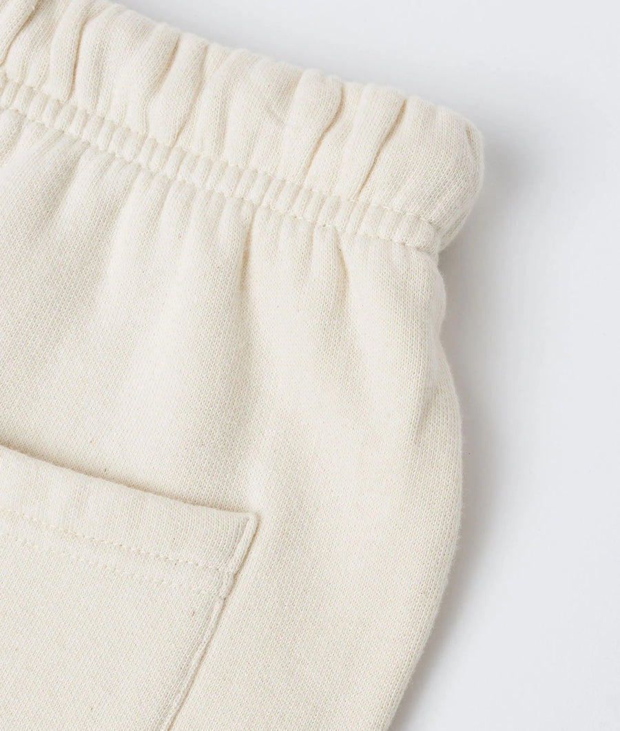 Detailed close-up image of a cream-colored, organic cotton sweatshirt with a ruched waistband - Industry of All Nations