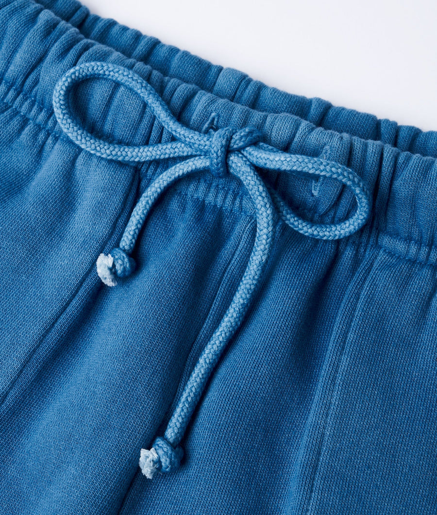 Close-up detail shot of a pair of blue cotton drawstring shorts with a braided tie closure - Industry of All Nations