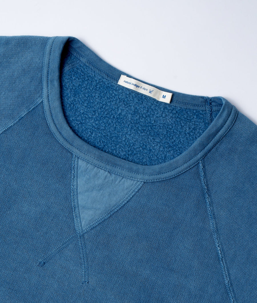 Close-up of a blue fleece sweatshirt featuring a nature indigo dyed color and contrasting stitching details - Industry of All Nations