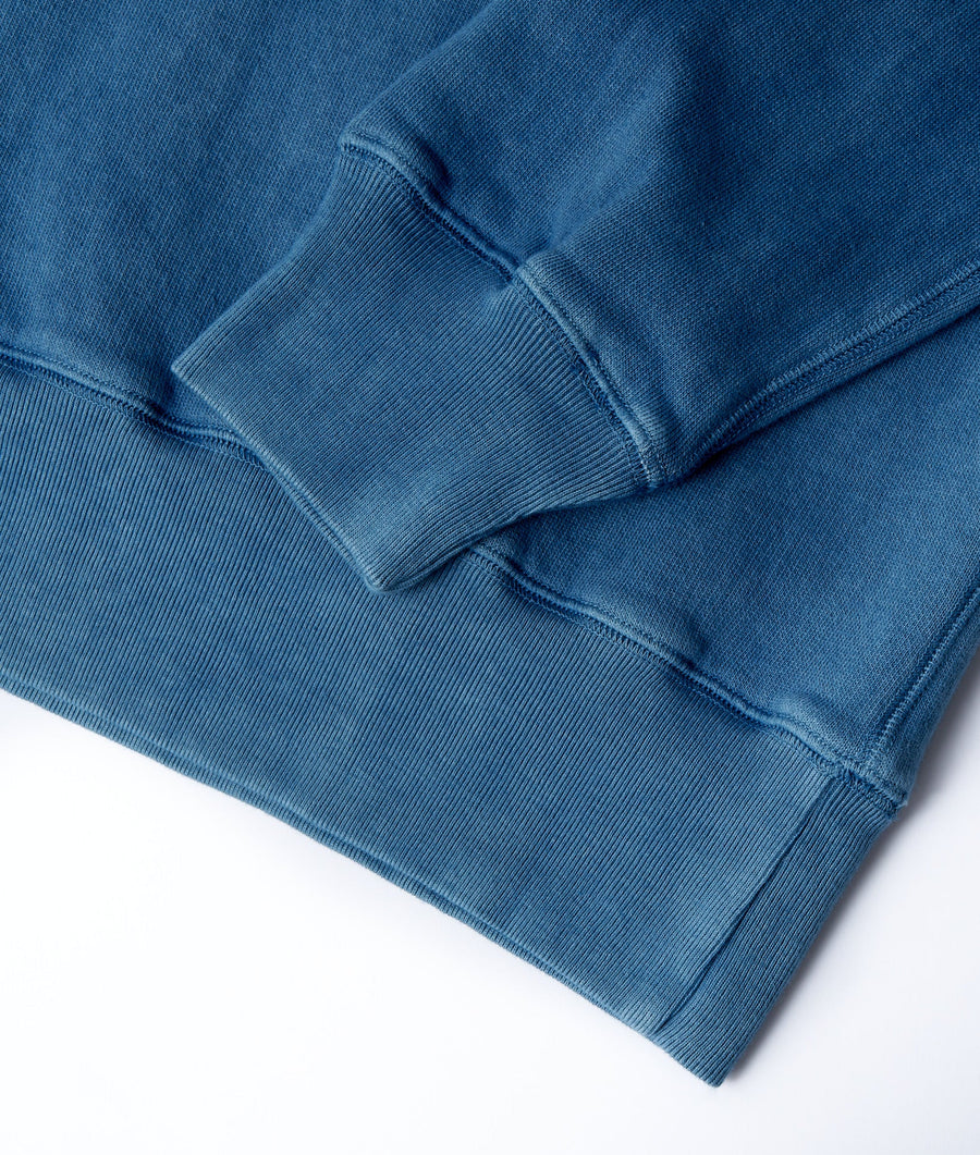 Detail shot of a dark blue cotton garment with ribbed cuffs and hem - Industry of All Nations