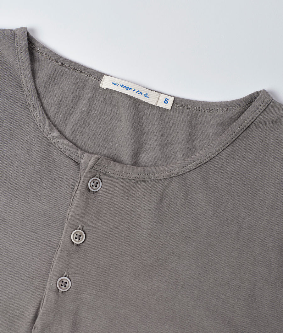 Flat lay of a gray cotton henley shirt with three buttons and a woven label reading "Iron vinegar 4 dies" - Industry of All Nations