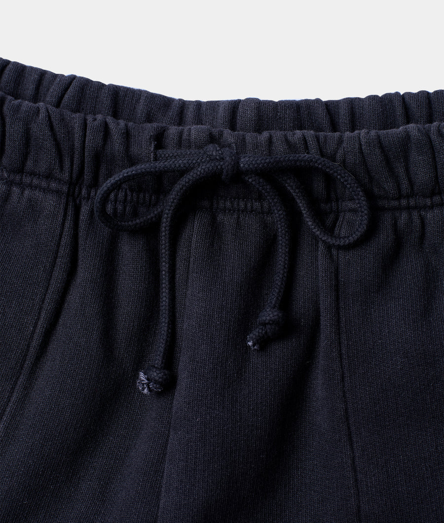 A close-up detail shot of the waistband and drawstring on a pair of black organic cotton sweatpants from Industry of All Nations.