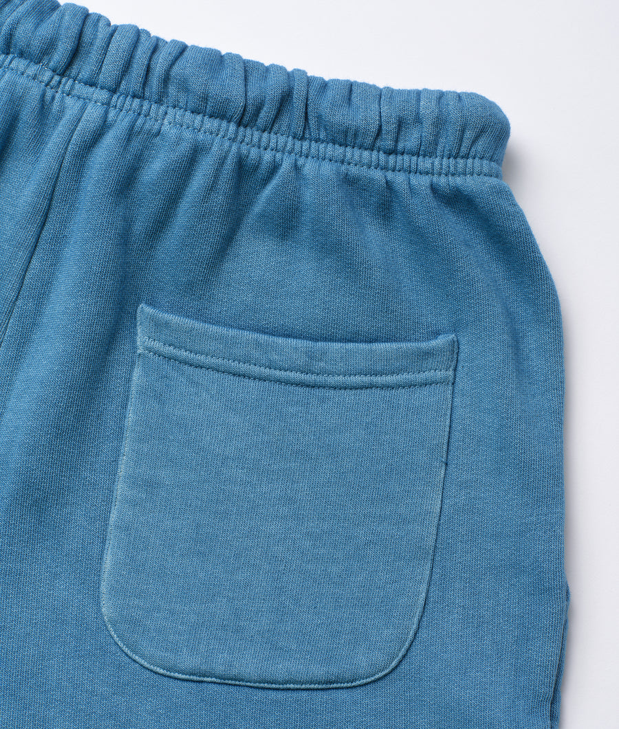 A close-up image of a pair of blue cotton drawstring sweatpants with a front pocket, displayed flat - Industry of All Nations