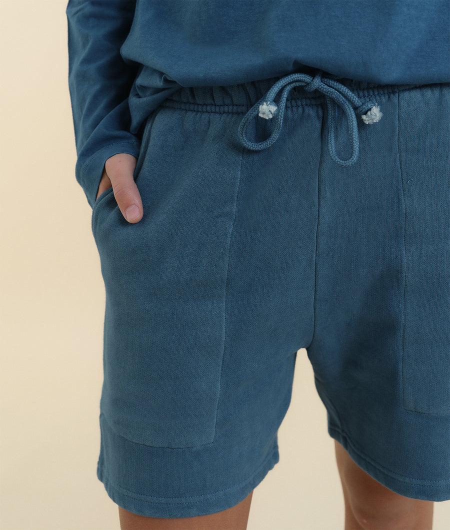 Close-up shot of a pair of dark blue drawstring shorts made of organic cotton, worn on a model - Industry of All Nations