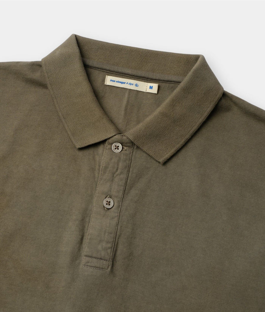 Close-up of a muted olive green polo shirt showing the collar, two-button placket, and inner neck label on a light gray background.