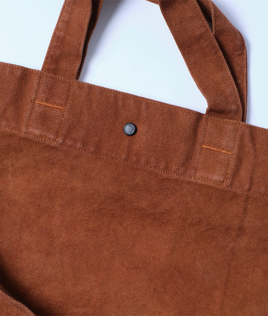 Close-up detail shot of a brown organic cotton tote bag with a single metal snap closure - Industry of All Nations