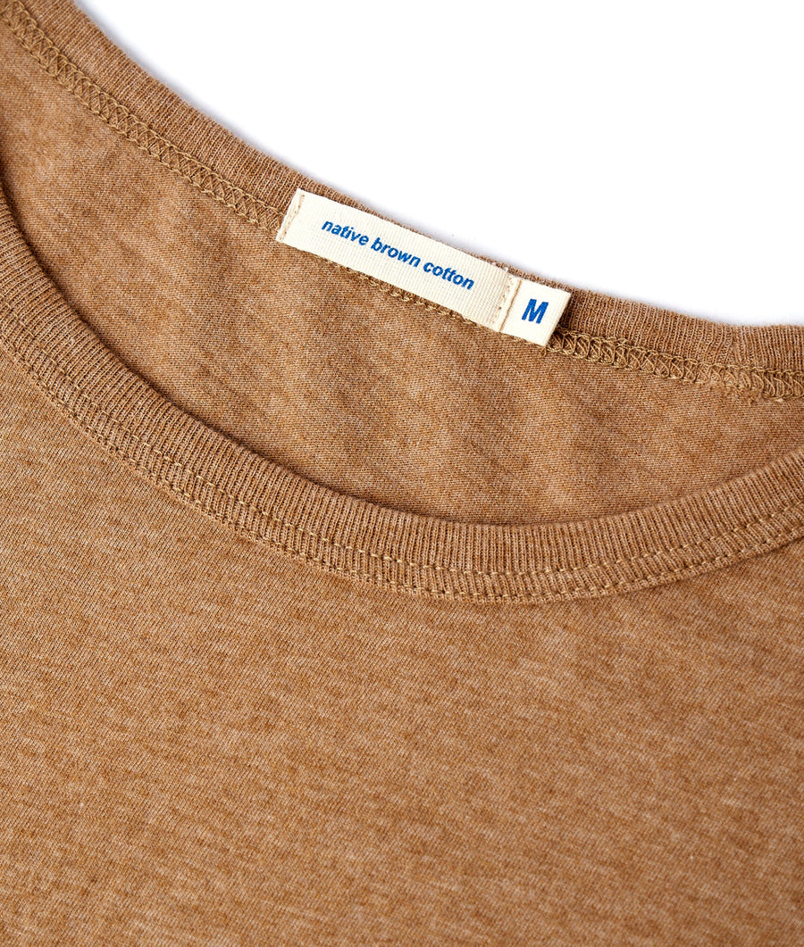 Detailed close-up shot of a tan/brown cotton t-shirt with a "Native Grown Cotton" label - Industry of All Nations
