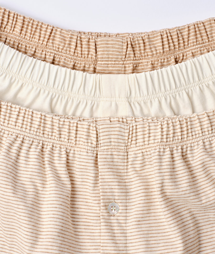 Close-up of striped organic cotton pajama bottoms in beige and off-white with a button closure detail - Industry of All Nations