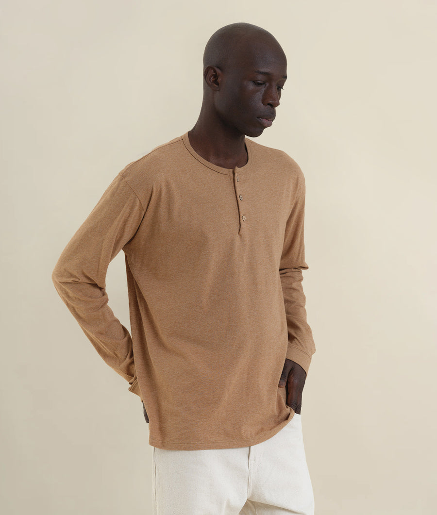 A model wearing a tan organic cotton henley shirt - Industry of All Nations