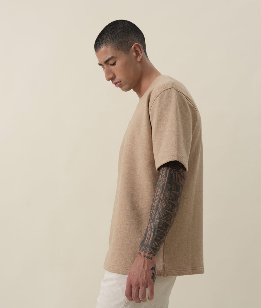 Tan oversized t-shirt with intricate tattoo sleeve design, worn on a male model - Industry of All Nations