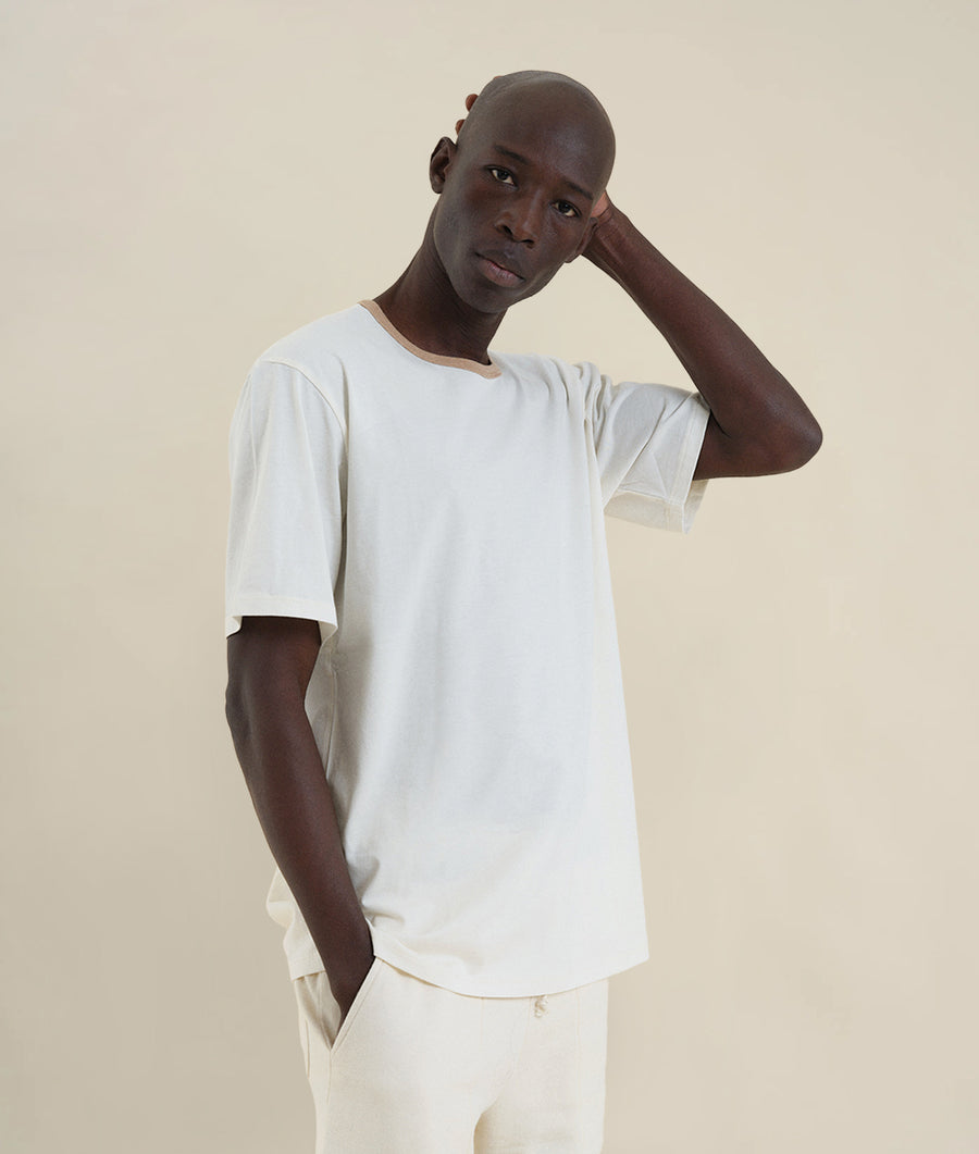 Portrait of a young Black man wearing a white short-sleeve t-shirt - Industry of All Nations
