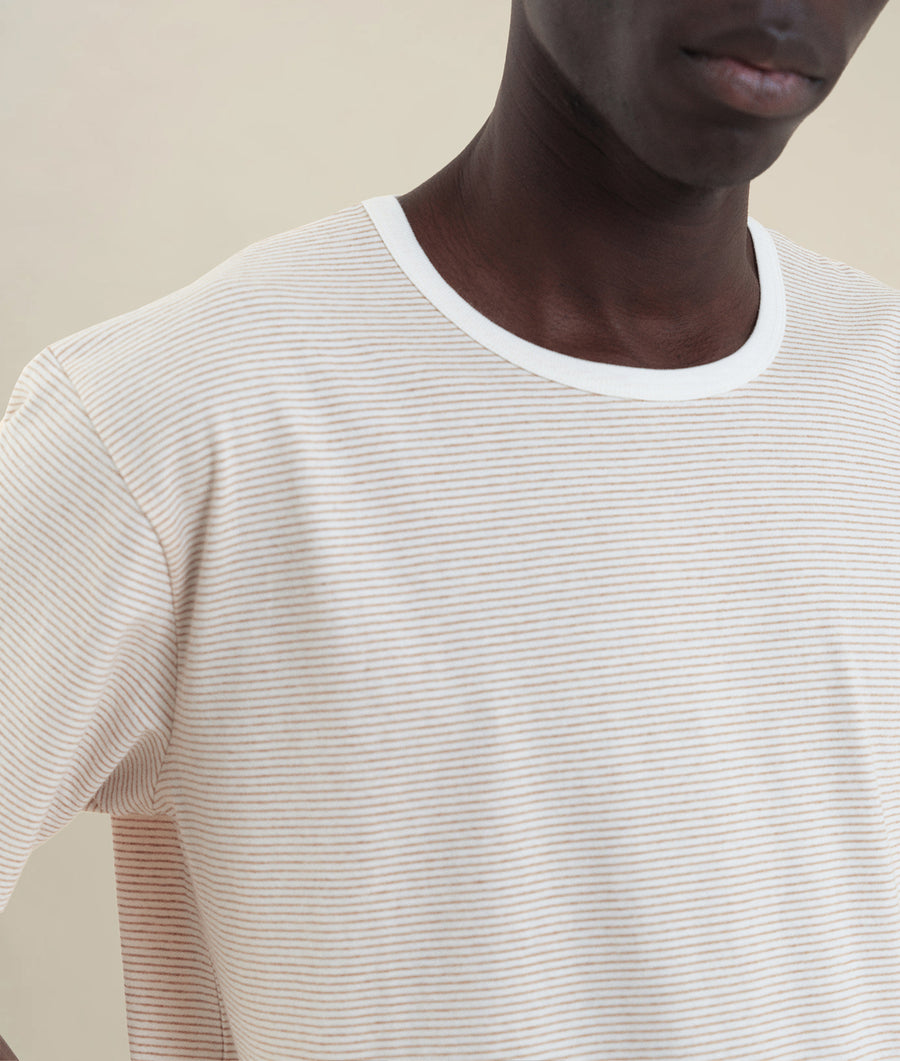 Closeup of a person wearing a white and beige striped t-shirt - Industry of All Nations