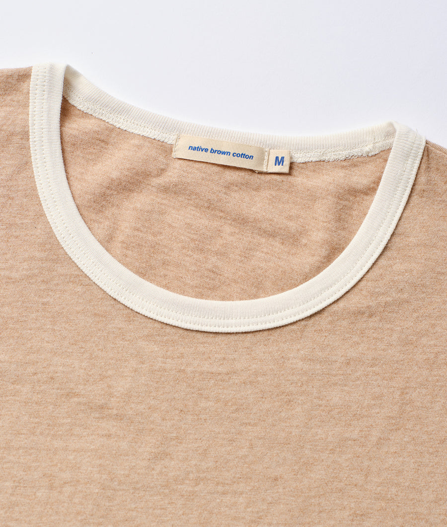 A close-up detail shot of the neck and label of a tan cotton t-shirt from the sustainable brand Industry of All Nations.