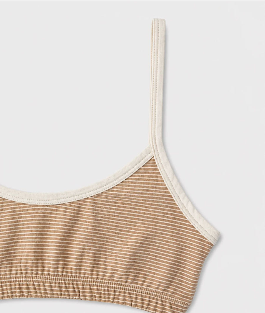 Close-up of the IOAN Wild Sport Bralette, featuring warm beige and white striped ribbed fabric with contrasting cream-colored underband and shoulder straps, against a light gray background.
