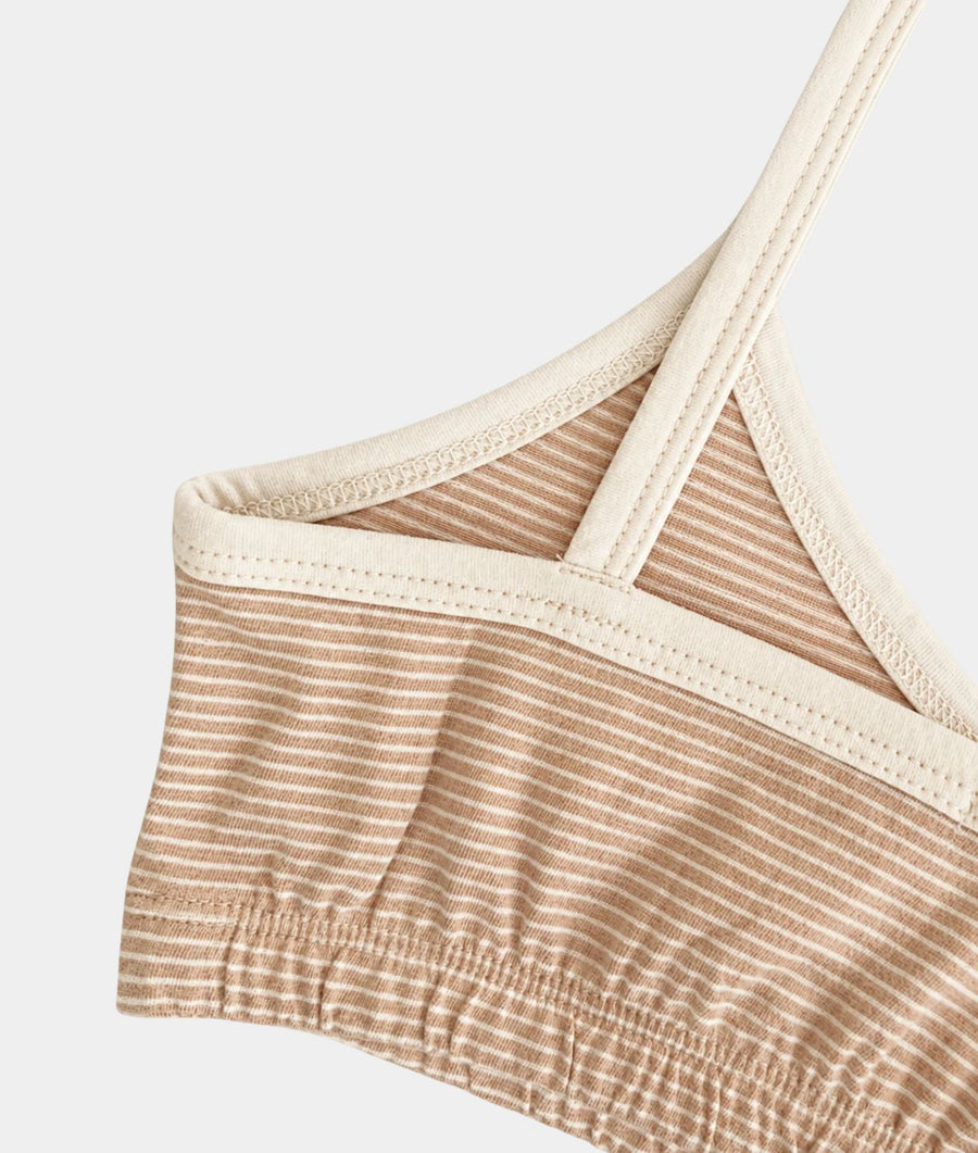 Close-up of the IOAN Wild Sport Bralette, showing the beige and white striped ribbed fabric, cream-colored trim, and shoulder strap against a light gray background.
