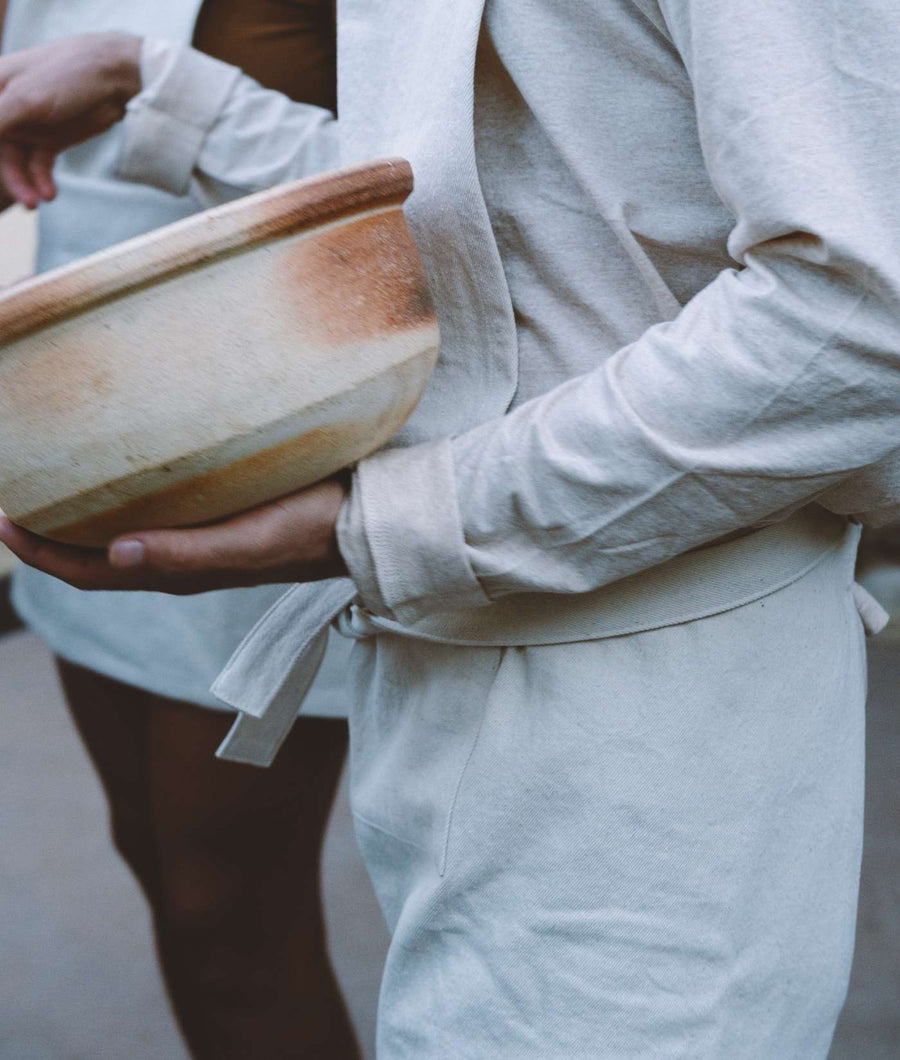 Closeup of a person wearing a white cotton robe or kimono with a wooden stool - Industry of All Nations