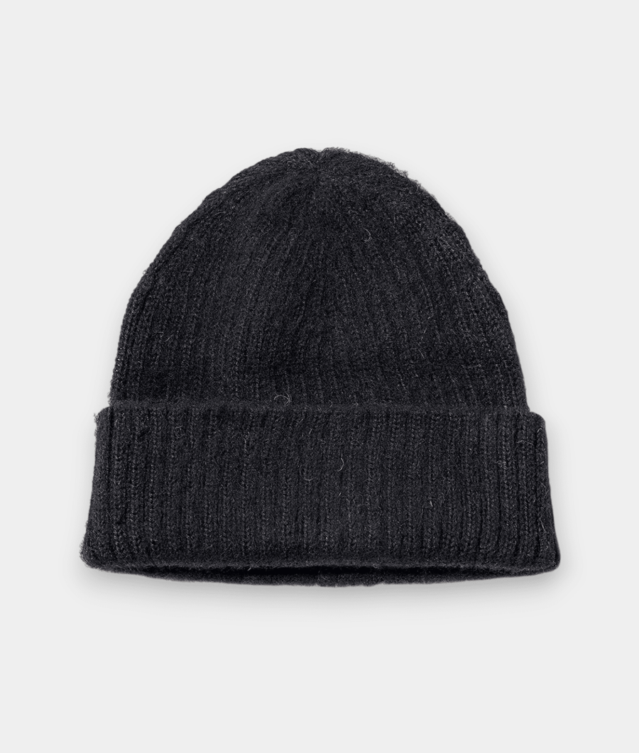 A black knitted beanie cap displayed in a flat lay - Industry of All Nations