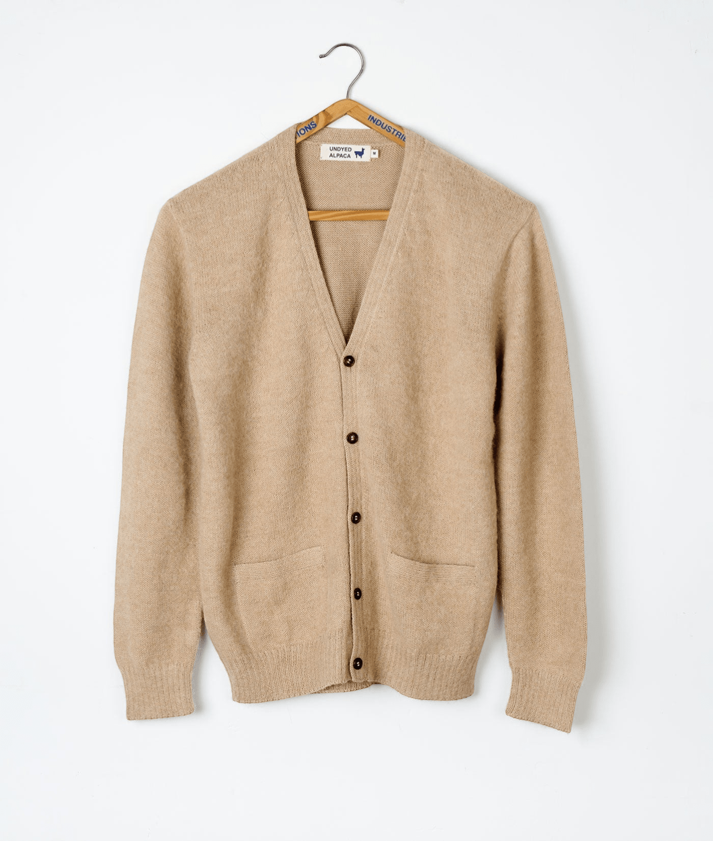 A beige alpaca wool cardigan sweater displayed on a wooden hanger - Industry of All Nations
