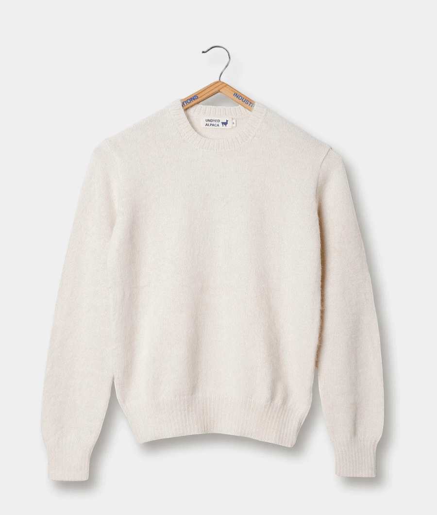 Cream-colored alpaca sweater, displayed on a wooden hanger - Industry of All Nations
