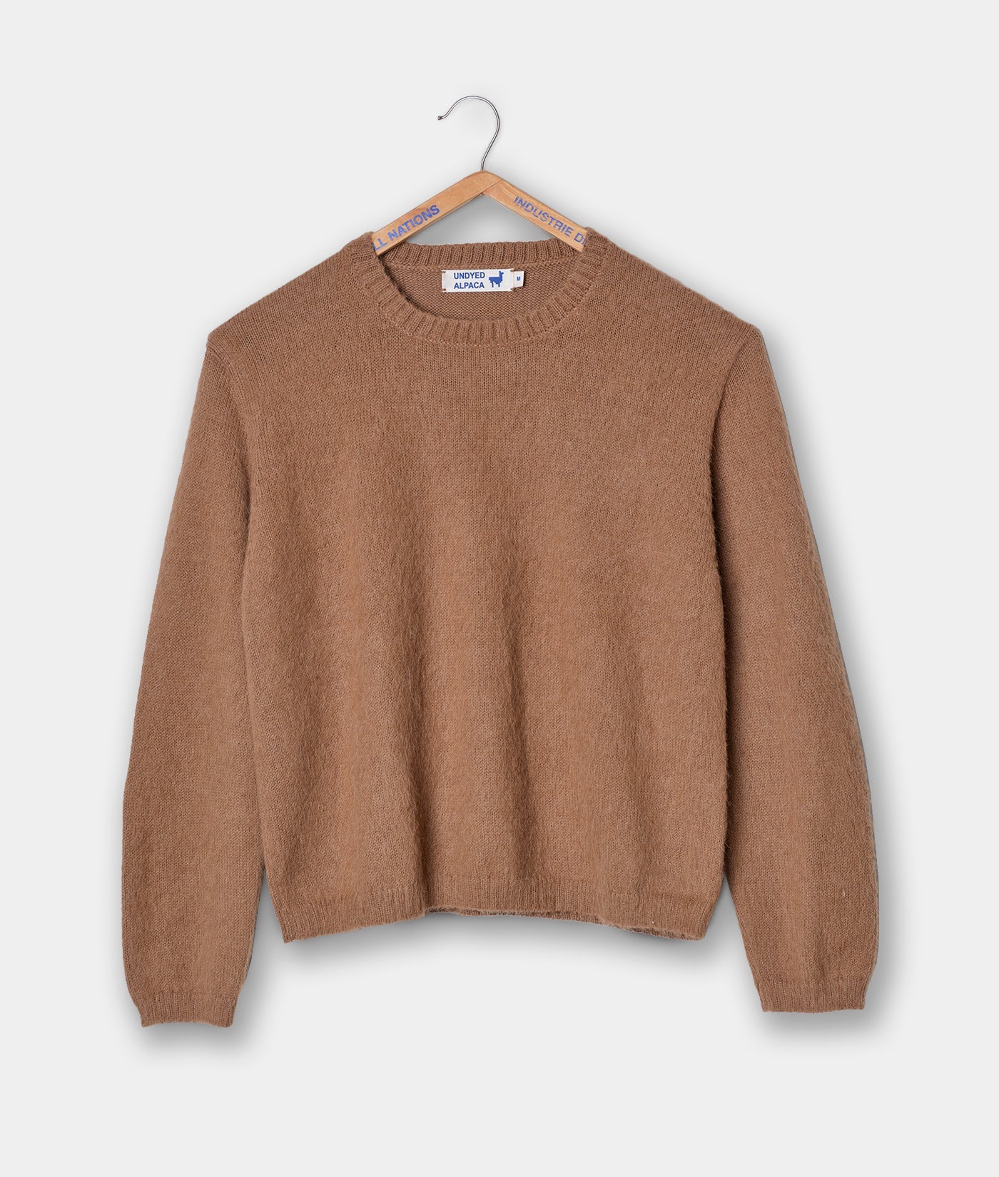 Tan alpaca sweater displayed flat on a white background with a hanger - Industry of All Nations