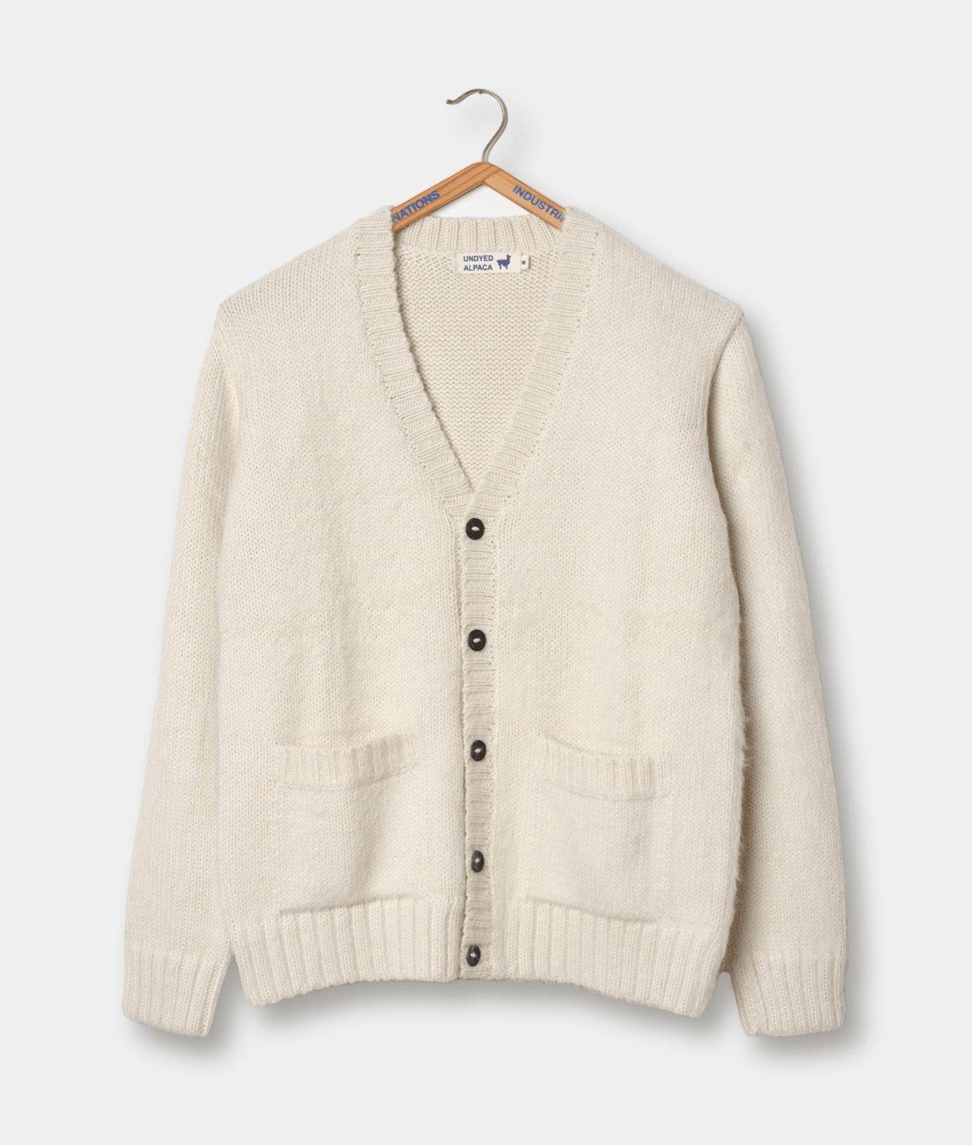 A cream-colored alpaca wool cardigan sweater displayed on a wooden hanger - Industry of All Nations