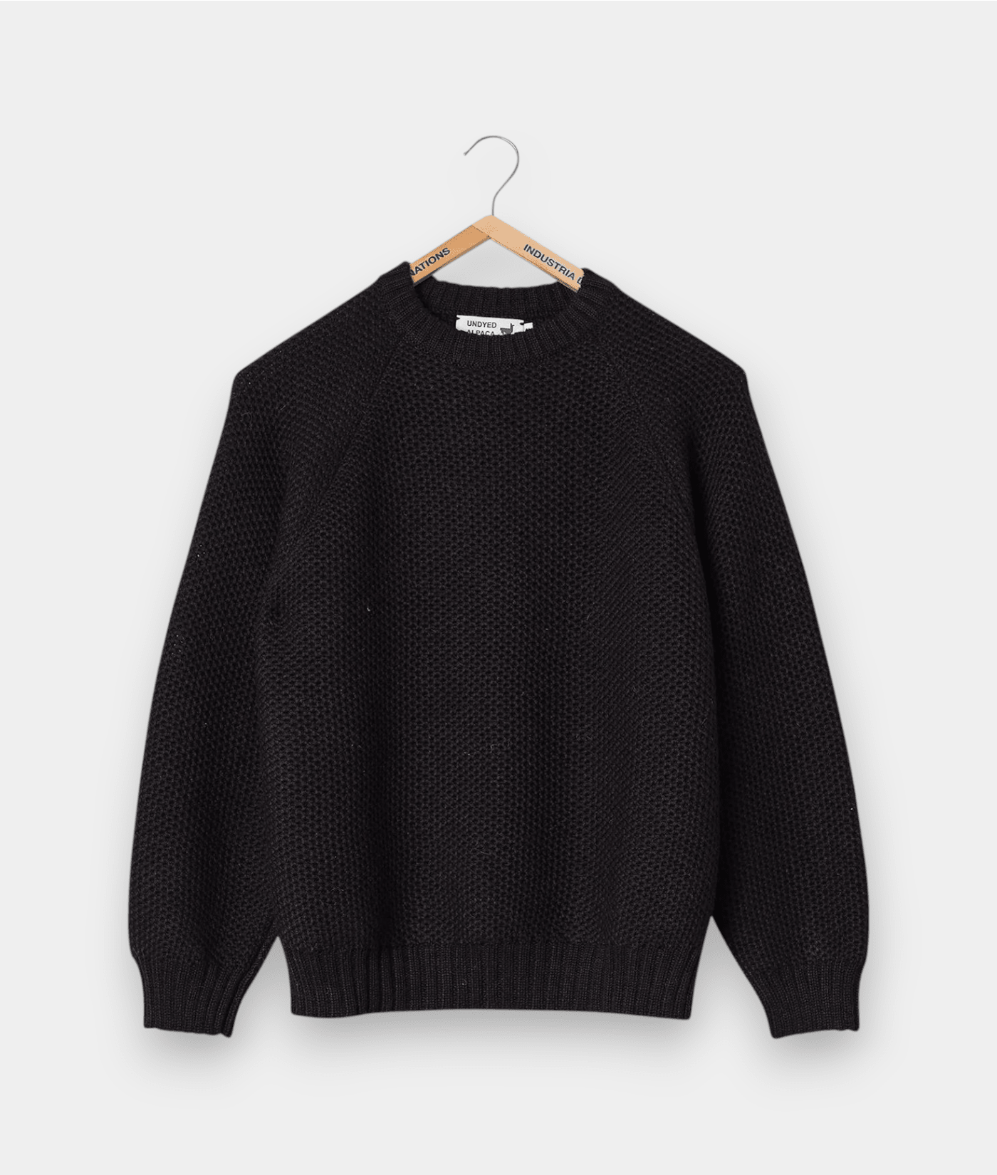 Black knitted pullover sweater with ribbed trim, displayed on a wooden hanger - Industry of All Nations