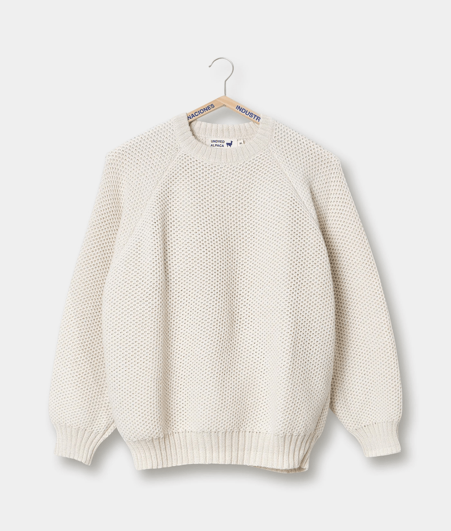 Cream-colored knitted sweater with patterned texture, displayed on a hanger - Industry of All Nations