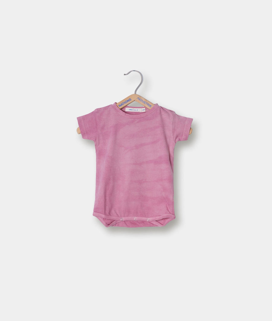 A plain pink/magenta onesie or bodysuit hanging on a grey wooden hanger - Industry of All Nations