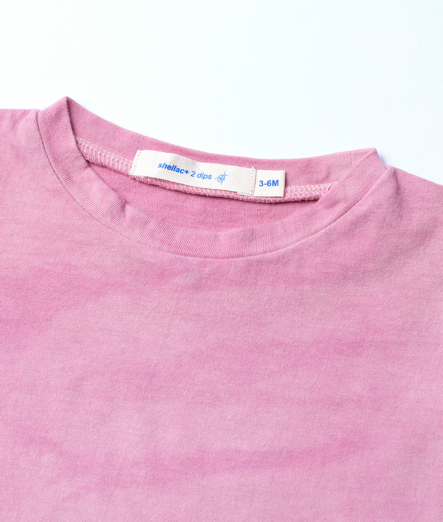 A close-up detail image of a pink ribbed cotton garment with a Sheliac + 2 dips 3-6M size label - Industry of All Nations
