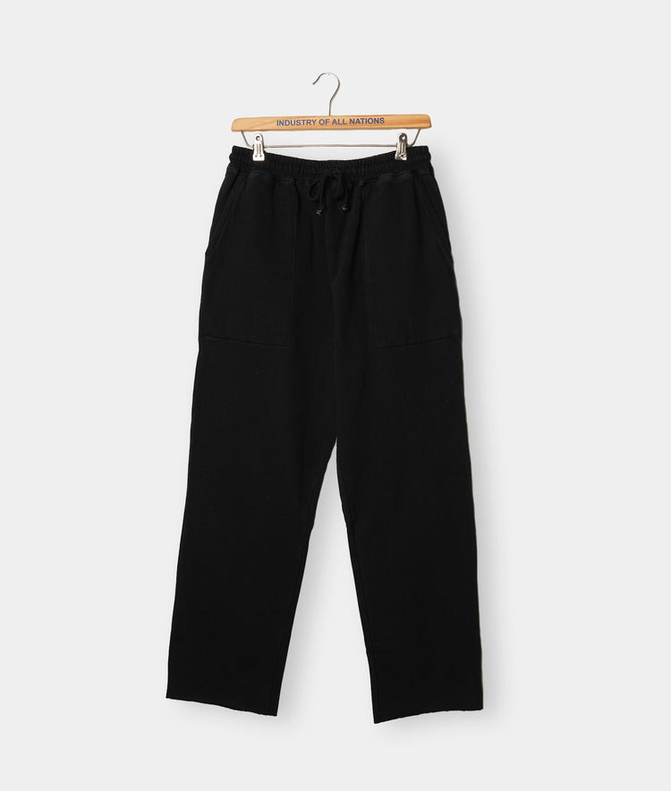 Black relaxed fit pants hanging on a wooden hanger against a white background - Industry of All Nations