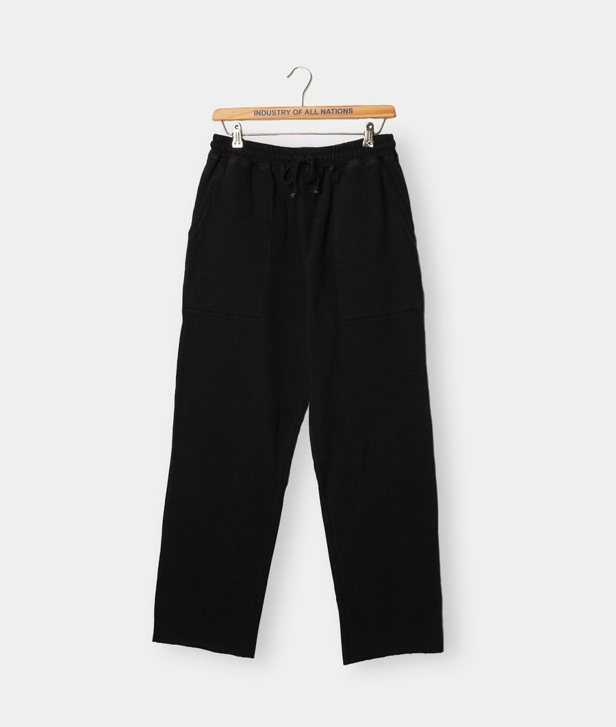 Black relaxed fit pants hanging on a wooden hanger against a white background - Industry of All Nations