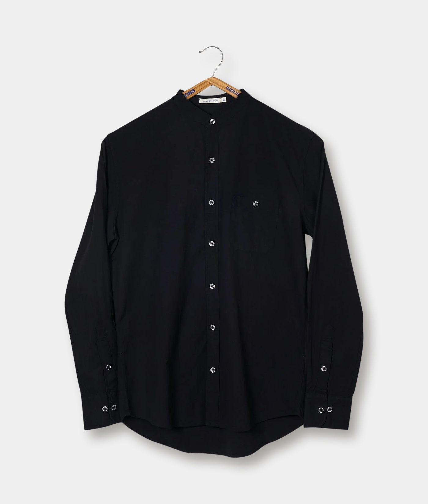 Black button-up shirt hanging on a clothing rack - Industry of All Nations