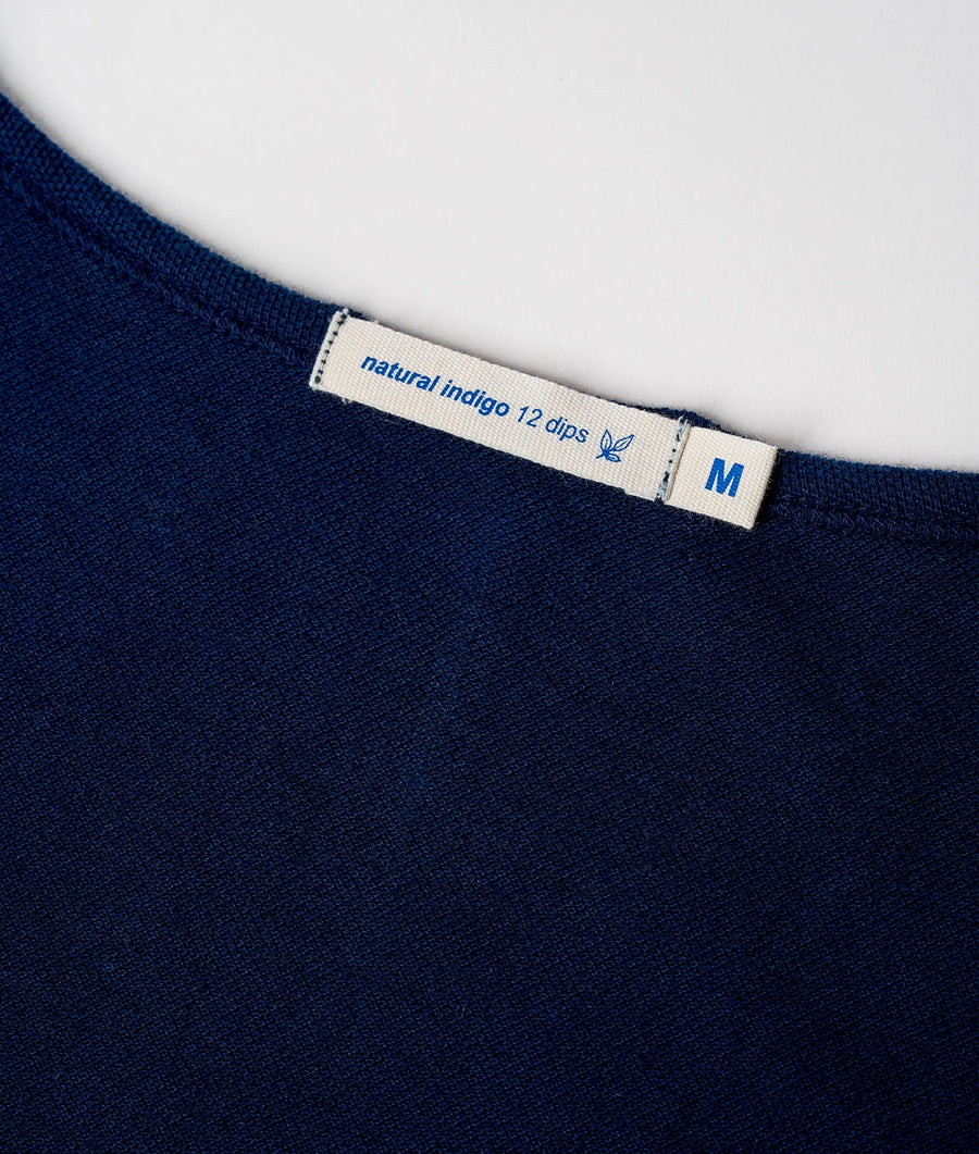 A close-up detail shot of a navy blue t-shirt with a natural indigo 12 dips label - Industry of All Nations