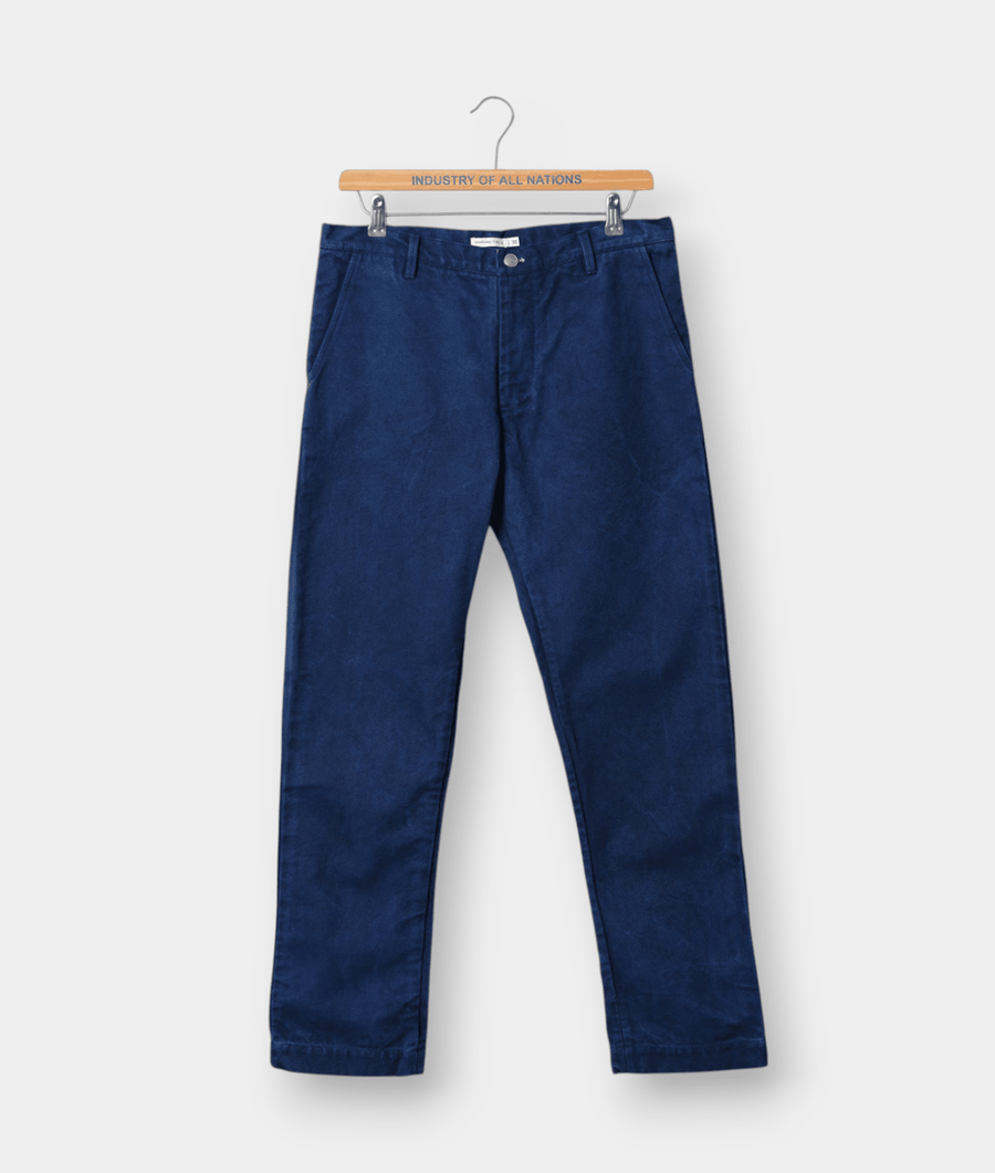 Navy blue cotton chinos hung on a wooden hanger with the brand name "Industry of All Nations" printed on it - Industry of All Nations