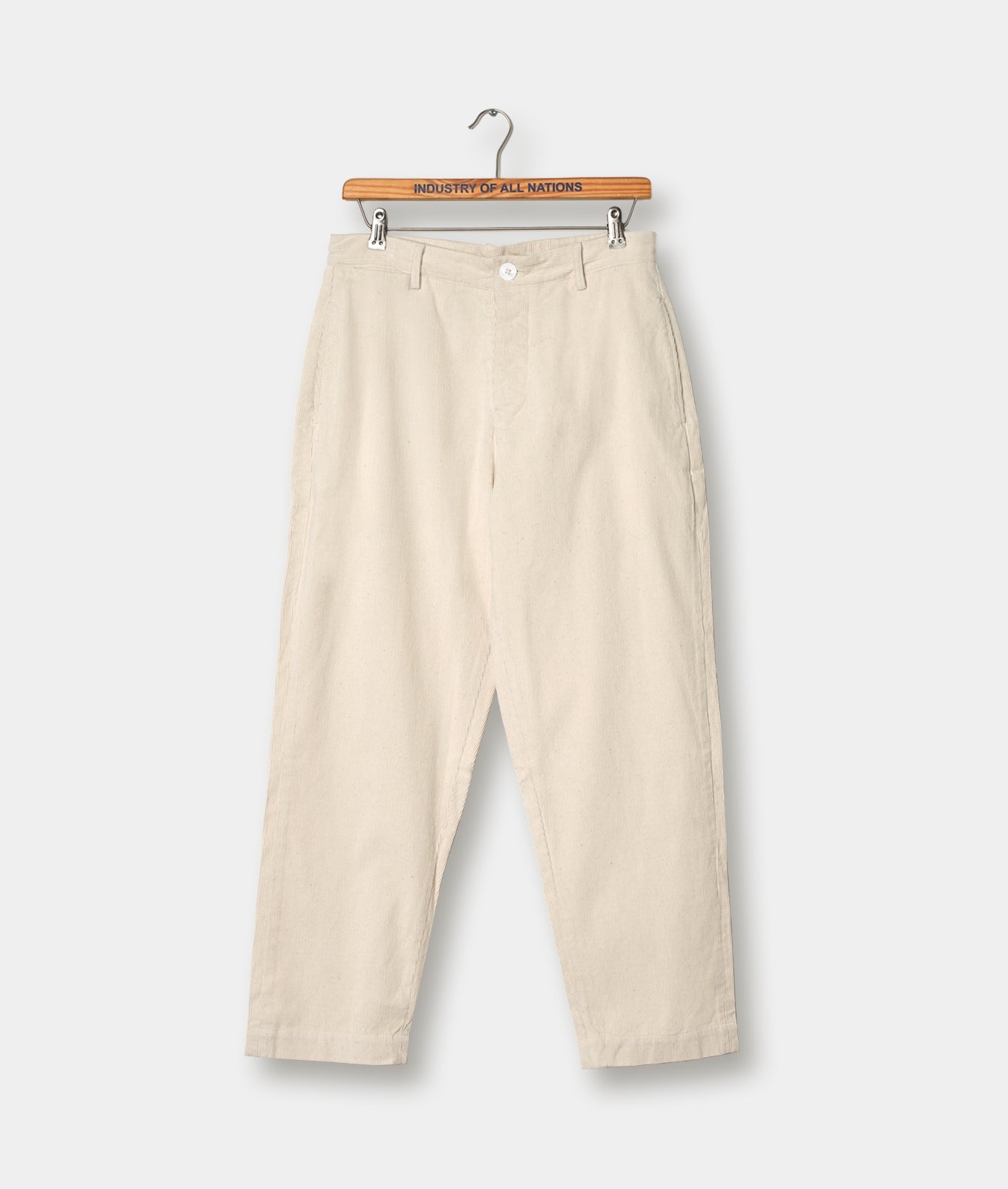 Beige cotton pants hanging on a wooden hanger with 'Industry of All Nations' printed on it - Industry of All Nations