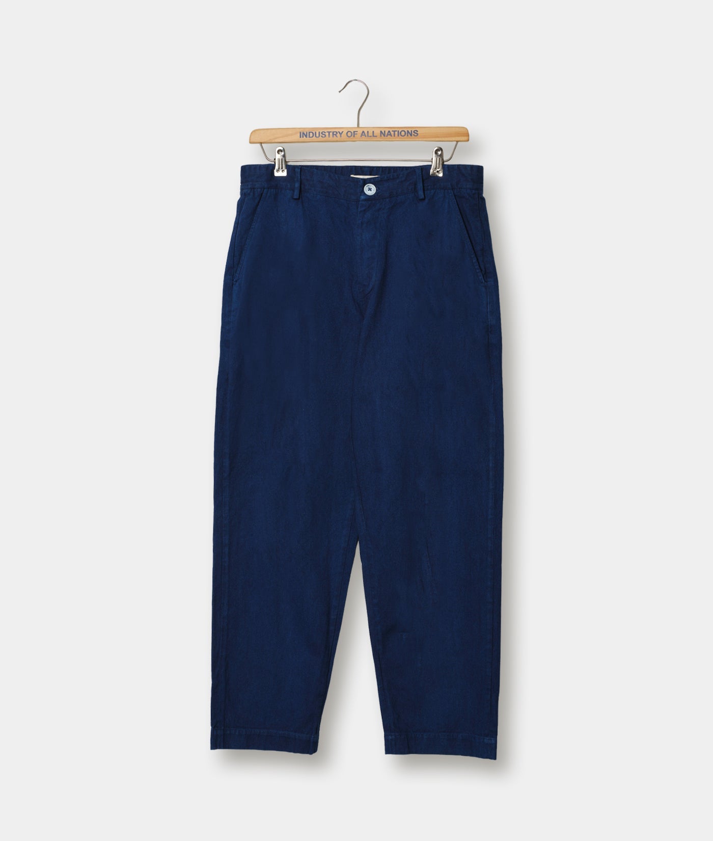 Navy blue chino pants displayed on a wooden hanger with "Industry of All Nations" branding - Industry of All Nations
