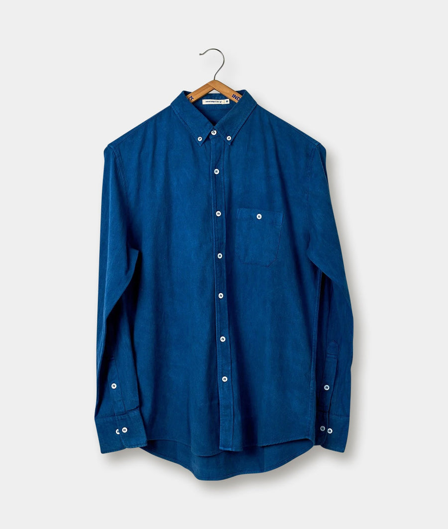 Blue button-down shirt hanging on wooden hanger - Industry of All Nations