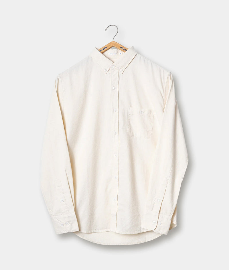 A cream-colored button-down shirt hanging on a wooden hanger - Industry of All Nations