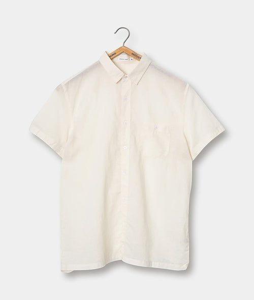 Cream-colored button-down shirt, hung on a wooden hanger against a plain background - Industry of All Nations