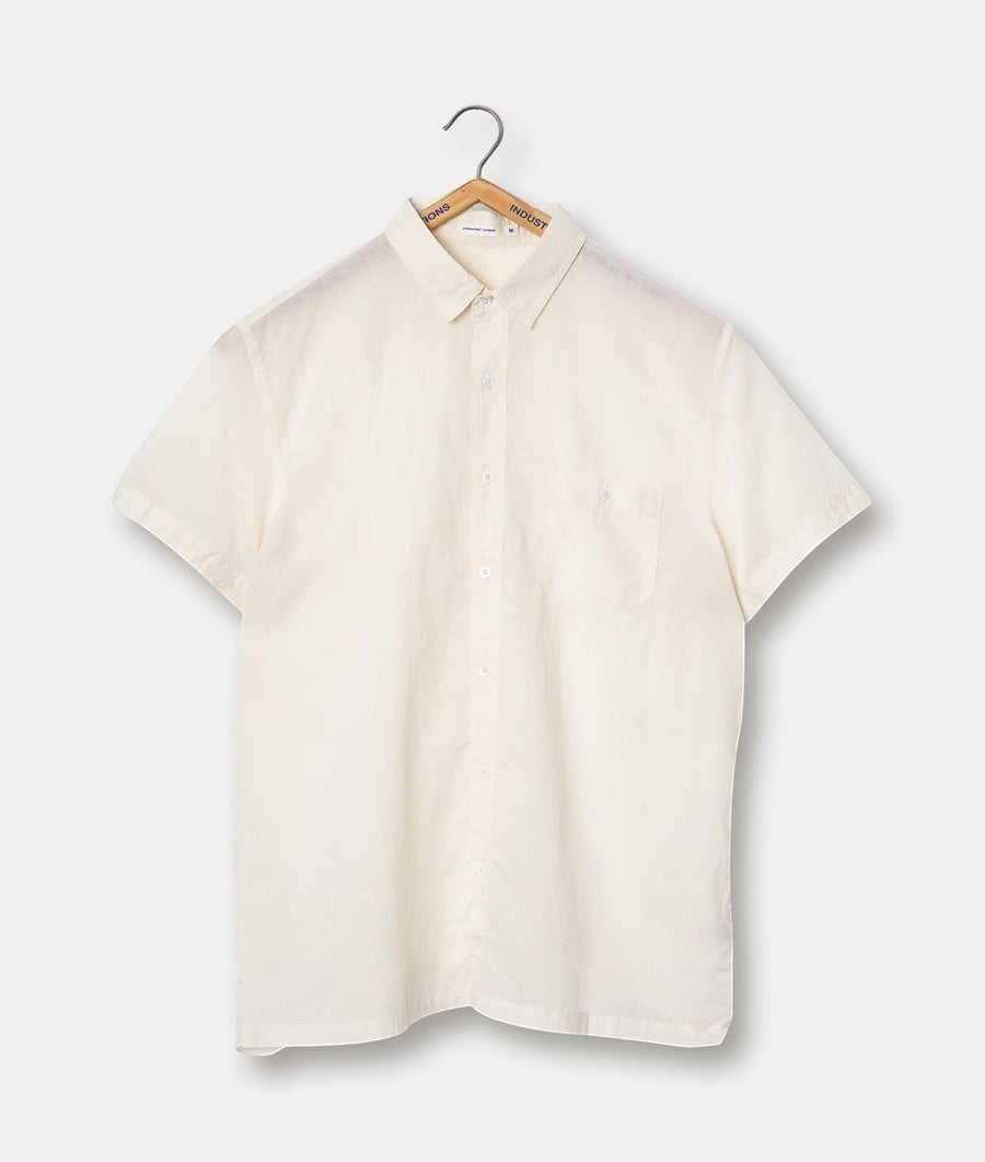 Cream-colored button-down shirt, hung on a wooden hanger against a plain background - Industry of All Nations