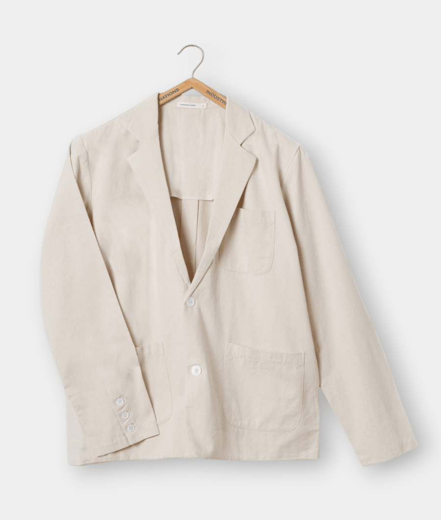 Beige cotton blazer hanging on a wooden hanger with "Industry" logo - Industry of All Nations